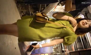 Kitang-kita sa harap ang candid shot ng YC mall ng magandang puting-collar na seksi na damit na panloob na may berdeng palda, brown na high heels, at itim na buhok at mga marka ng butas.