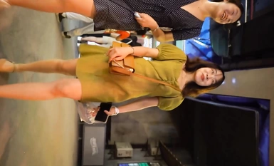 Kitang-kita sa harap ang candid shot ng YC mall ng magandang puting-collar na seksi na damit na panloob na may berdeng palda, brown na high heels, at itim na buhok at mga marka ng butas.